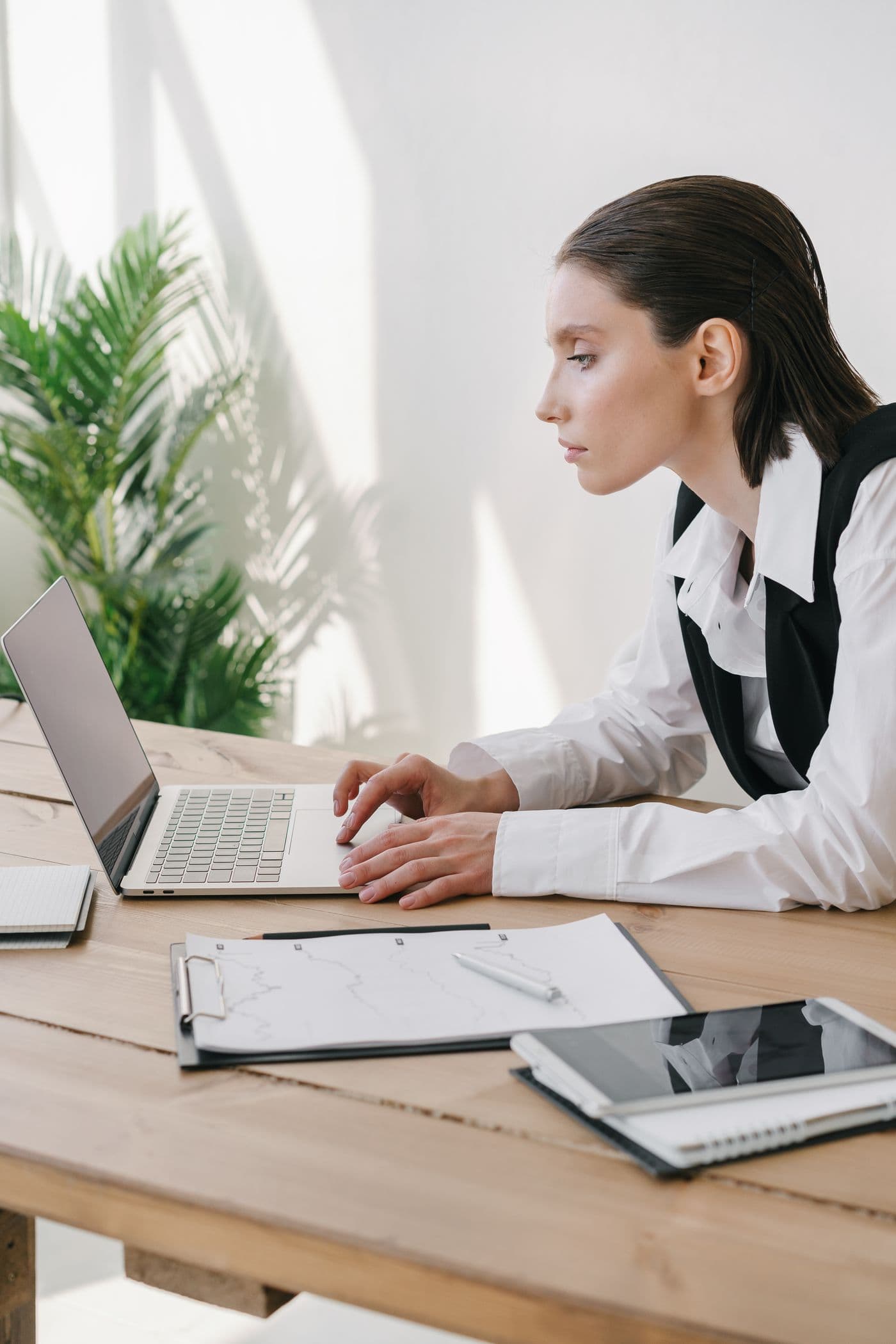 Une femme travaille sur un ordinateur portable dans un bureau moderne, des documents à côté.