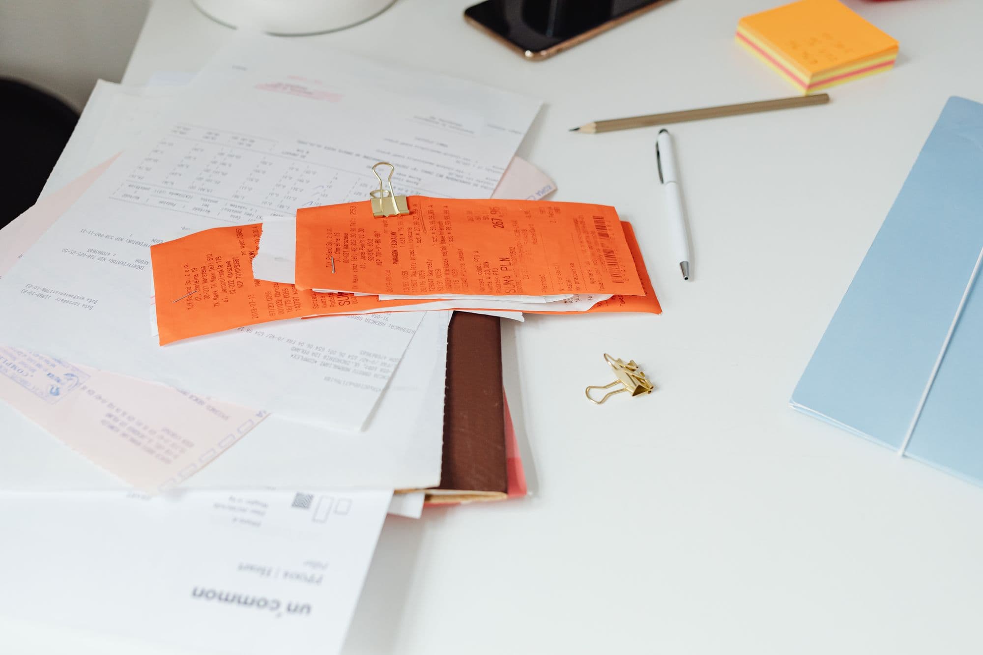 Un bureau bien rangé avec des reçus, des documents et de la papeterie.